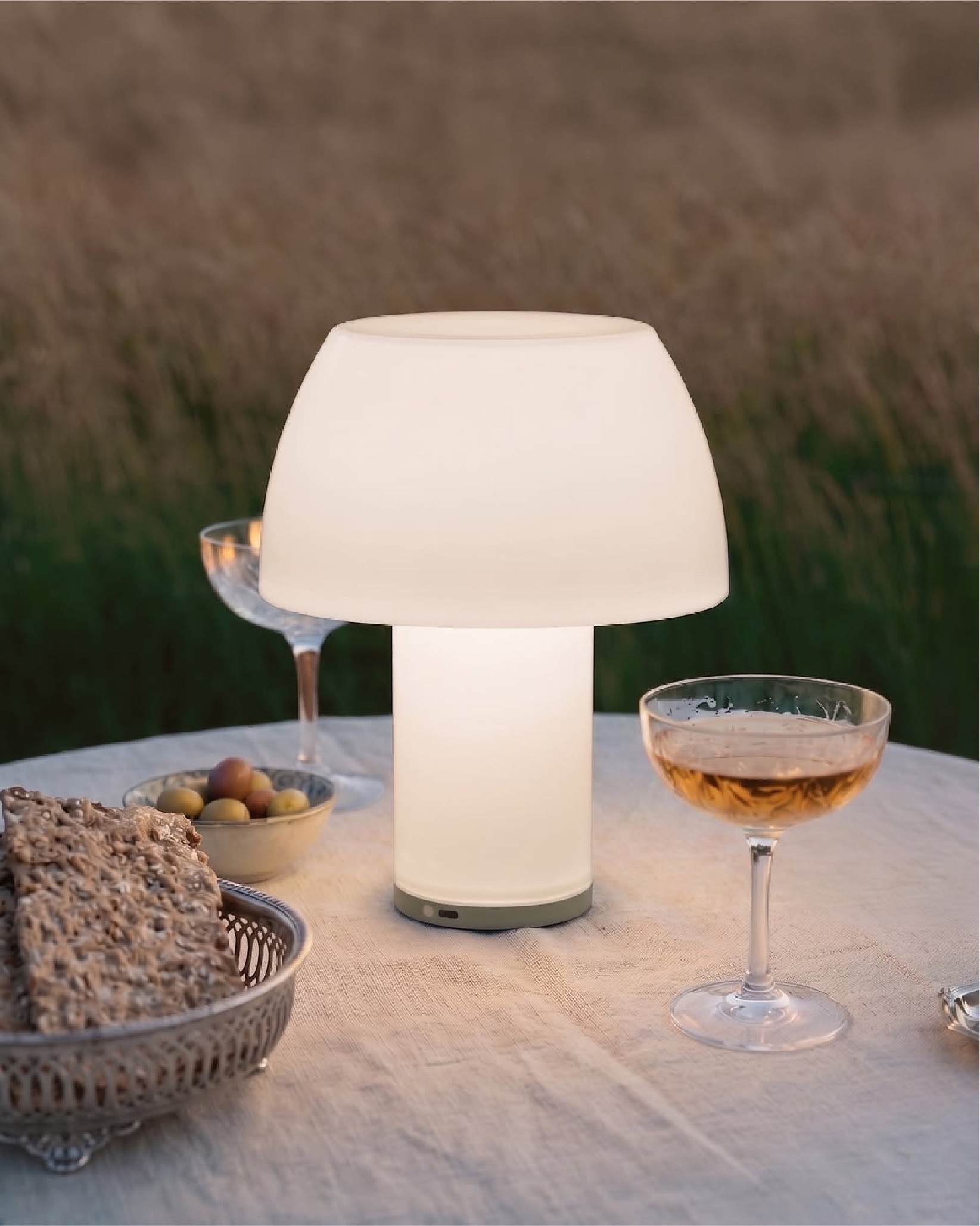 Glowing portable table lamp beside cocktail glasses on an outdoor table